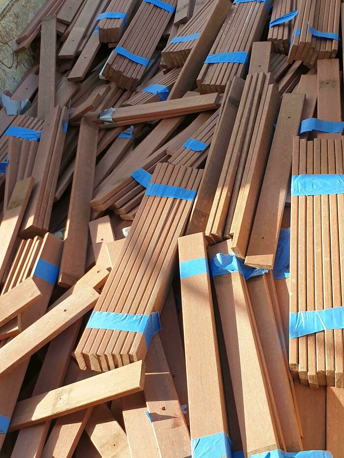 A pile of wooden planks, some bound with blue tape, representing the surprising price difference in consumerism.