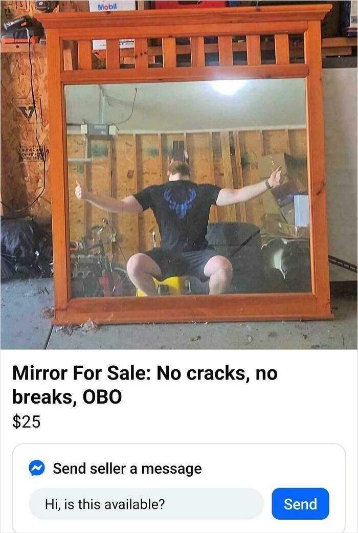 Large wooden framed mirror reflecting a person posing with thumbs up in a cluttered garage setting for bizarre online sale listings.