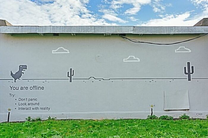 Street art of offline dinosaur game on a wall with funny pieces of advice about staying calm and interacting with reality.