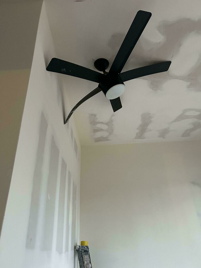 A ceiling fan installed incorrectly, partially on a wall, showcasing a funny you had one job fail.