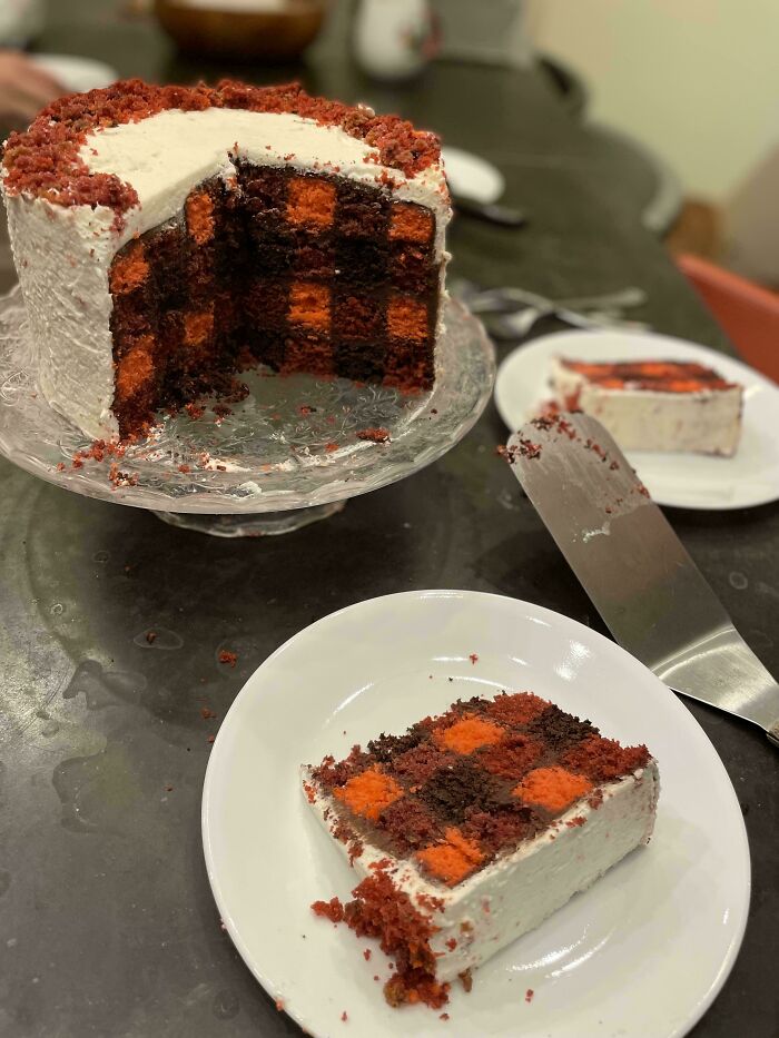 Checkered red velvet dessert cake with white frosting sliced on plate