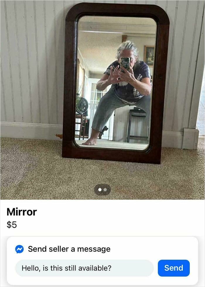 Person pulling off a creative pose perfectly while taking a mirror selfie in a room with carpet and white walls.