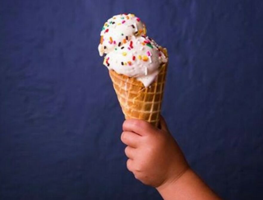 Child holding ice cream cone with sprinkles against dark blue background, illustrating fun facts about joy in learning.