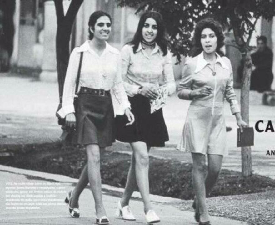 Three women walking outdoors in vintage 1970s clothing, enjoying a moment of learning interesting and fun facts.