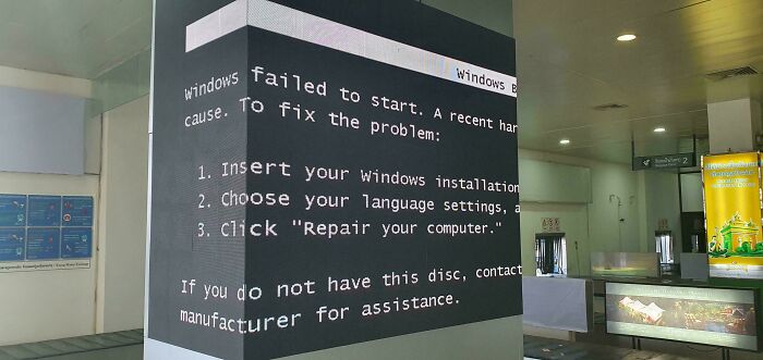 A large digital display in an airport shows a Windows error message, illustrating the chaotic place.