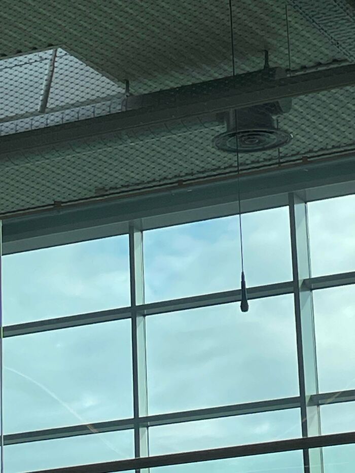 A microphone hangs from the ceiling in an airport, highlighting the chaotic place.