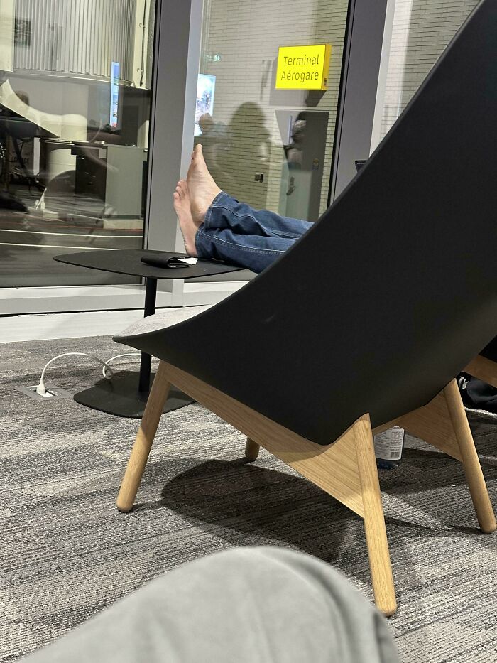 A person with bare feet resting on a table at a busy airport terminal, highlighting a chaotic place on the planet.