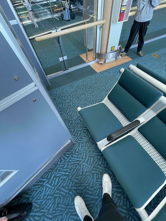 An empty airport waiting area with teal patterned carpet and modern seating, reflecting moments of airport chaos.