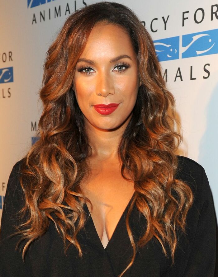 Leona Lewis with wavy hair and red lipstick at a charity event, highlighting her bio and career achievements.