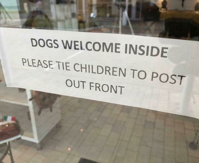A humorous sign reads Dogs Welcome Inside, Please Tie Children to Post Out Front. An oddly specific rule.