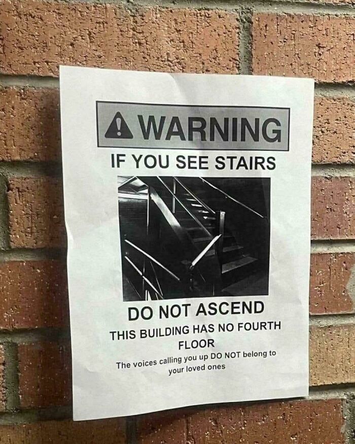 A warning sign on a brick wall about stairs leading to a non-existent fourth floor, reminiscent of oddly specific rules.
