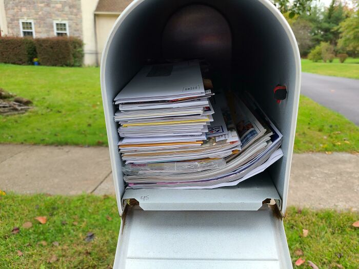 Stack of mail inside an open mailbox on a suburban street, representing strange and disturbing things found in elevator pits.