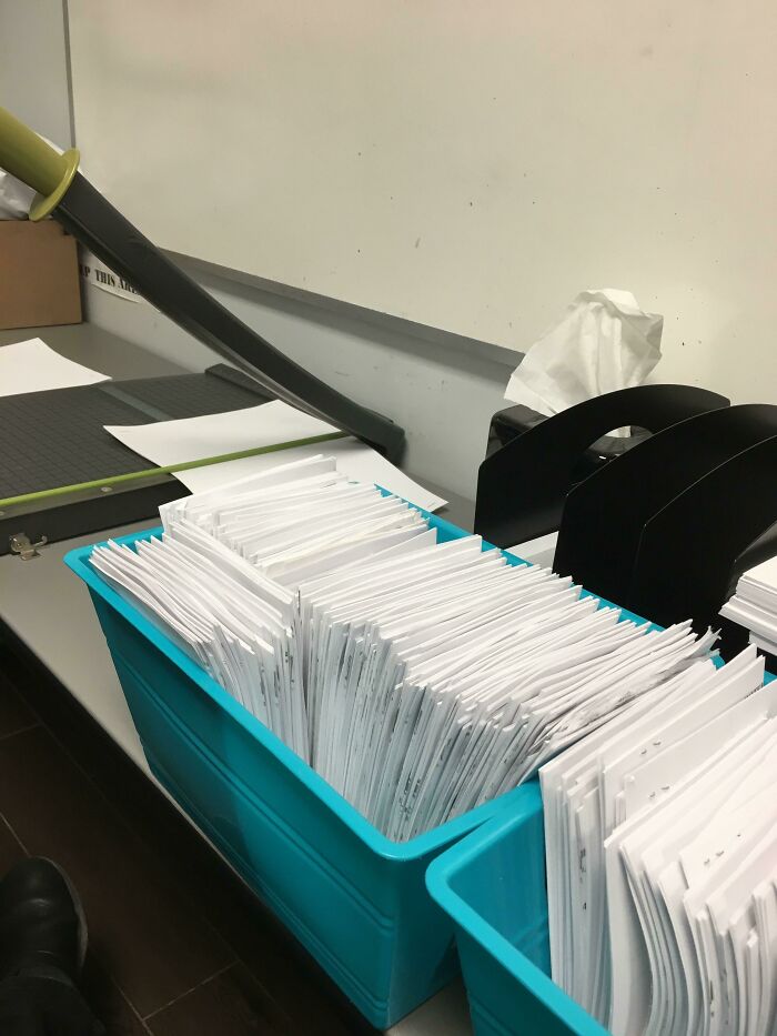 Blue bins filled with neatly stacked paper documents on a desk, related to strange and disturbing elevator pits.