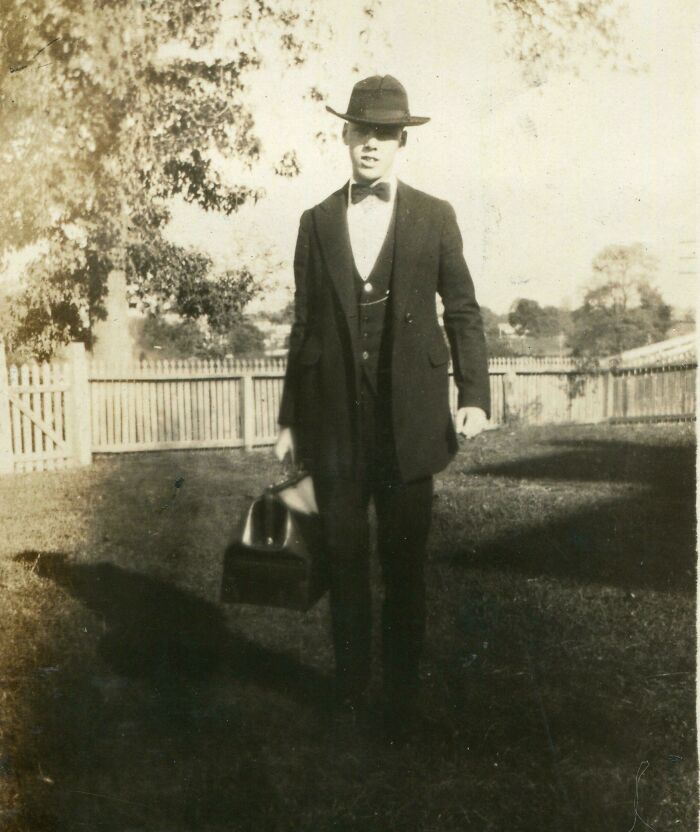 Candid old photo of a formally dressed man with a hat and briefcas, revealing what the world looked like generations ago.