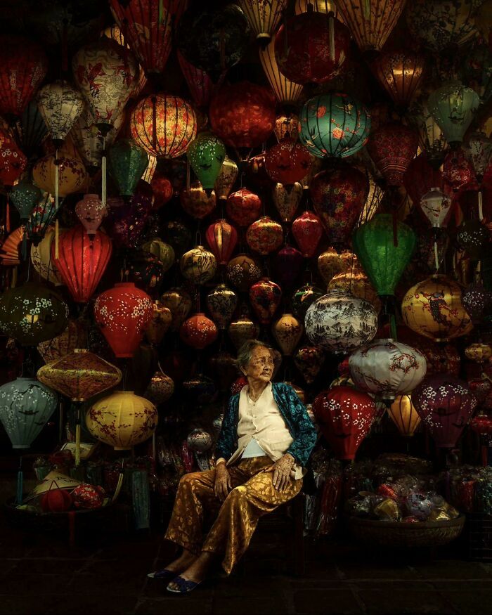 An elderly woman sitting amidst glowing lanterns, capturing an Accidental Renaissance aesthetic.