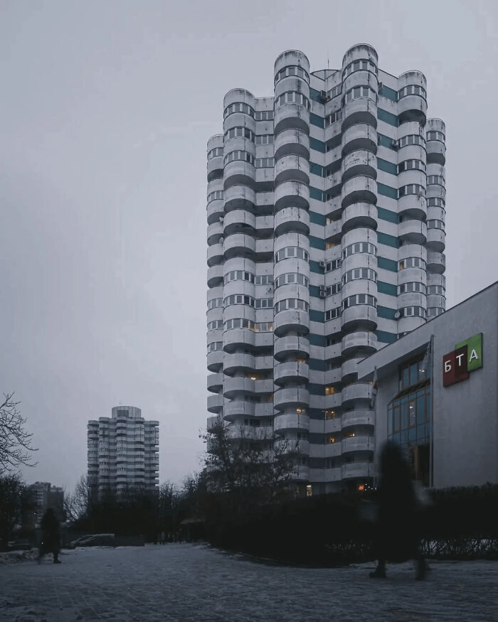 Tall residential tower with cylindrical balconies under gloomy urban sky
