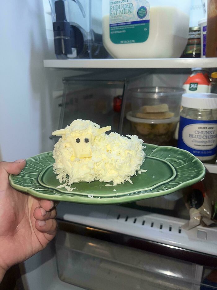 A handmade project of a butter lamb on a green plate, inside a refrigerator. It looks like it took talent.