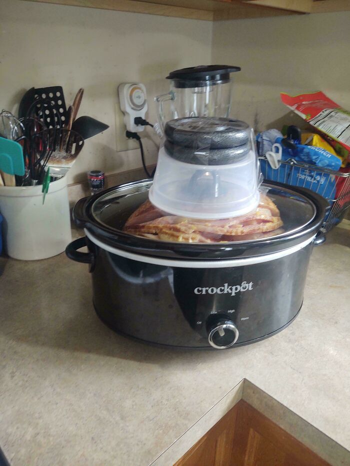 A crockpot with a plastic container on top of its lid to keep it closed, a clever solution for cooking.