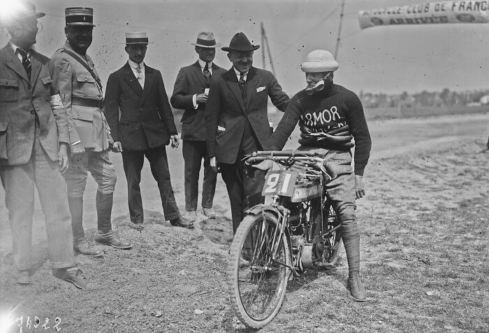 Early 20th century rare and interesting photo of a motorcycle racer with spectators in period attire at a race event.