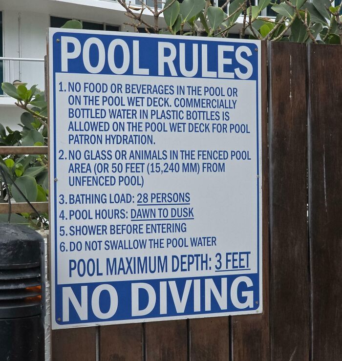 A white and blue pool rules sign, featuring oddly specific rules, including No Diving and Shower Before Entering.