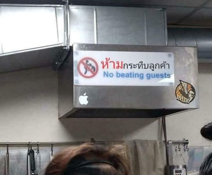 A sign in Thai and English on a metal vent reads No beating guests, an oddly specific rule that makes one wonder who inspired it.