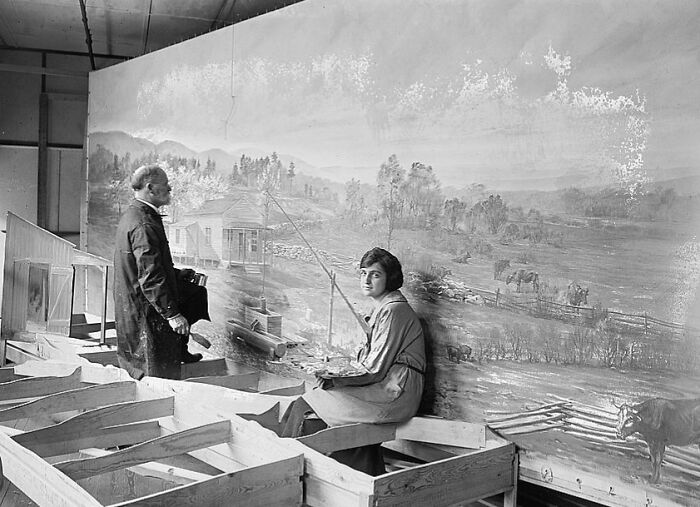 Black and white photo of two people painting a large rural landscape mural, a rare and interesting moment from the past.