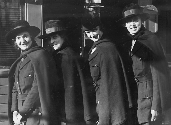 Four women in vintage military uniforms and hats smiling, a rare and interesting photo from a past era.