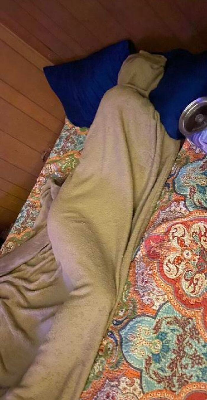 Person caught sleeping wrapped tightly in a blanket on a colorful bed, showcasing hilarious and unhinged sleeping ways.