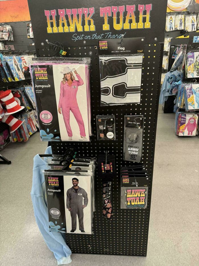 Display of Hawk Tuah costumes and merchandise including jumpsuits and accessories in a retail store setting showing unusual products.