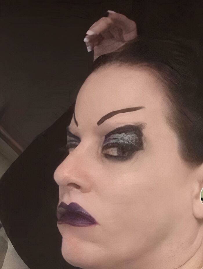 Woman with crazy eyebrows and dramatic dark eye makeup and lipstick seemingly living their own life on her face.