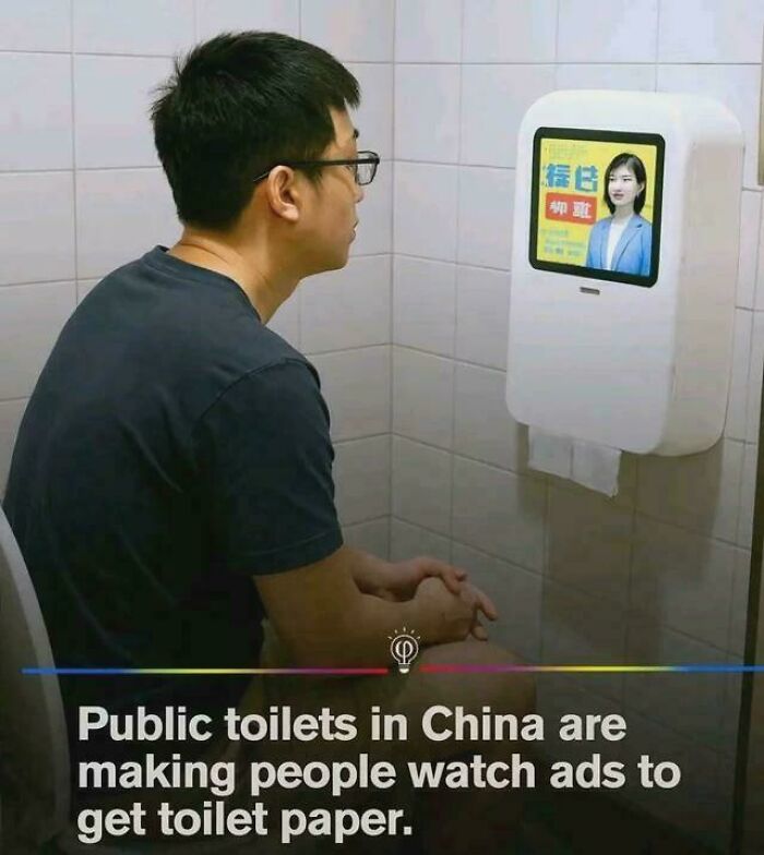 Man sitting in a public toilet watching ads on a screen to get toilet paper, illustrating modern depressing posts.