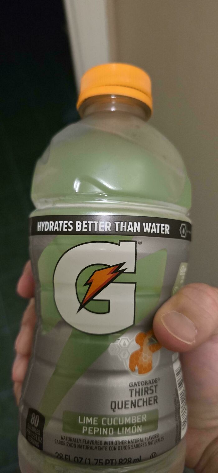Hand holding a lime cucumber flavored Gatorade bottle with a label claiming it hydrates better than water.