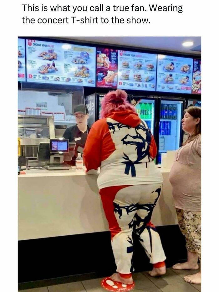 Person wearing full KFC-themed outfit at fast food counter, illustrating a depressing post about living in a foolish time.