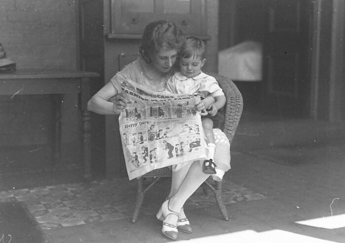 Vintage photo of a woman and child reading a newspaper, showcasing rare and interesting moments from the past.