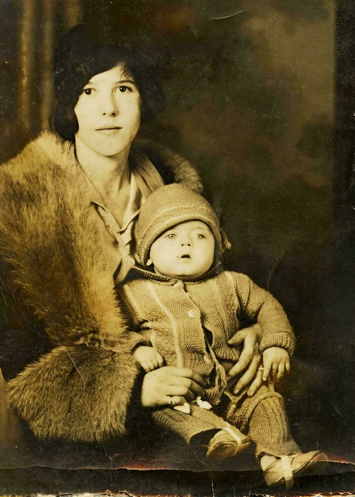Vintage photo of a woman in a fur coat holding a baby in knitted clothing, highlighting iconic photos from decades ago.