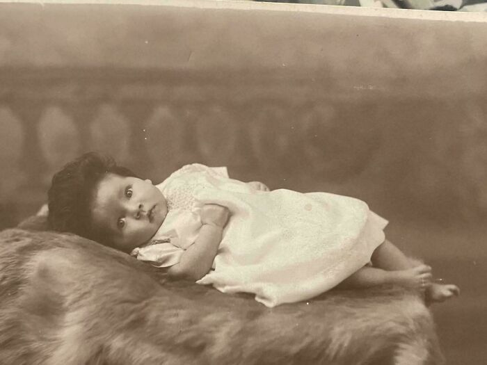 Vintage photo of a baby lying on a fur blanket, showcasing timeless moments from decades ago in historic photos.