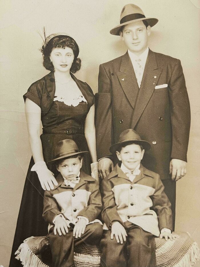 Vintage family portrait from decades ago showing parents and two boys dressed in classic attire and hats.