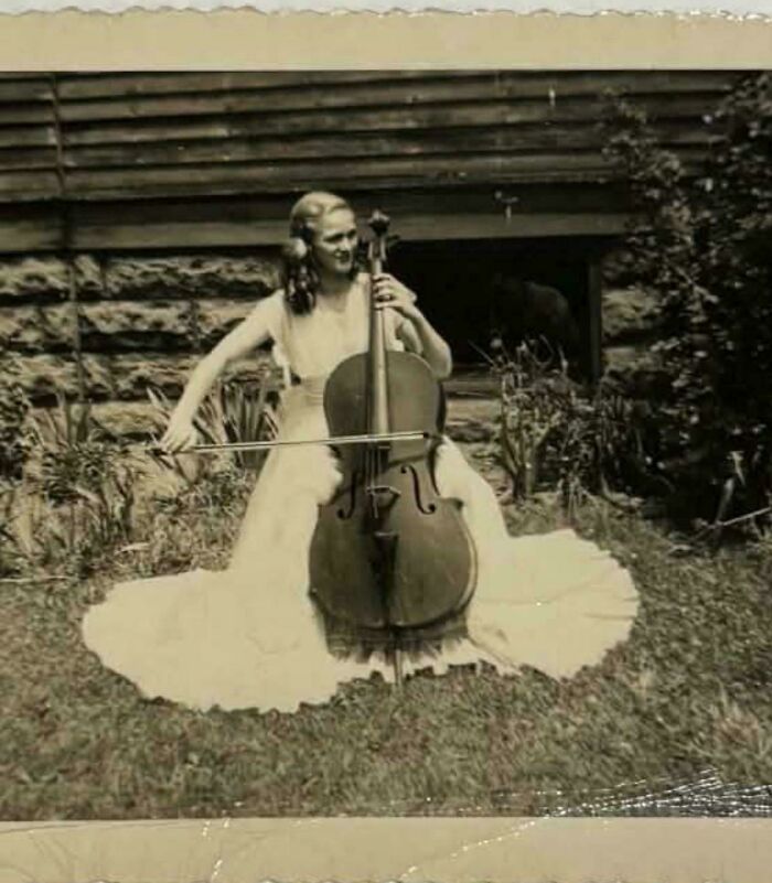 Vintage photo of a woman in a flowing dress playing cello outdoors, capturing moments from decades ago that speak louder today.