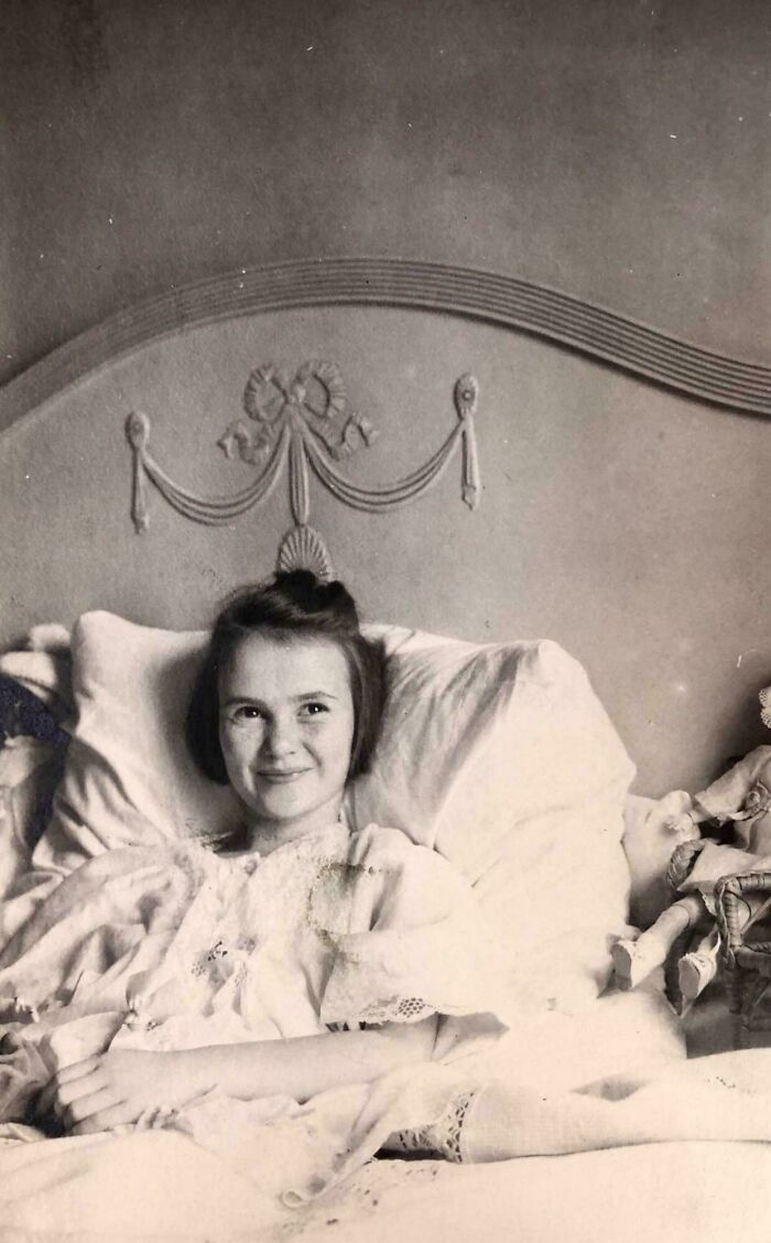 Black and white photo of a smiling girl in bed, a vintage image from decades ago that still speaks loudly today.