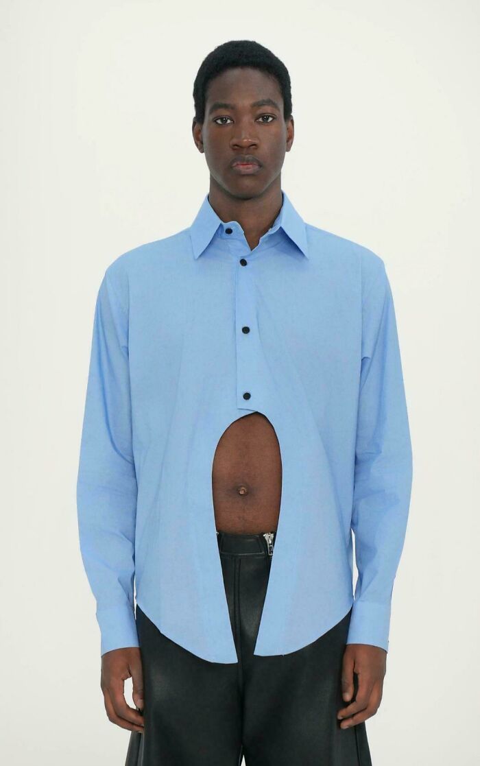 A man wearing a blue shirt with a large cutout, an example of cringey fashion.