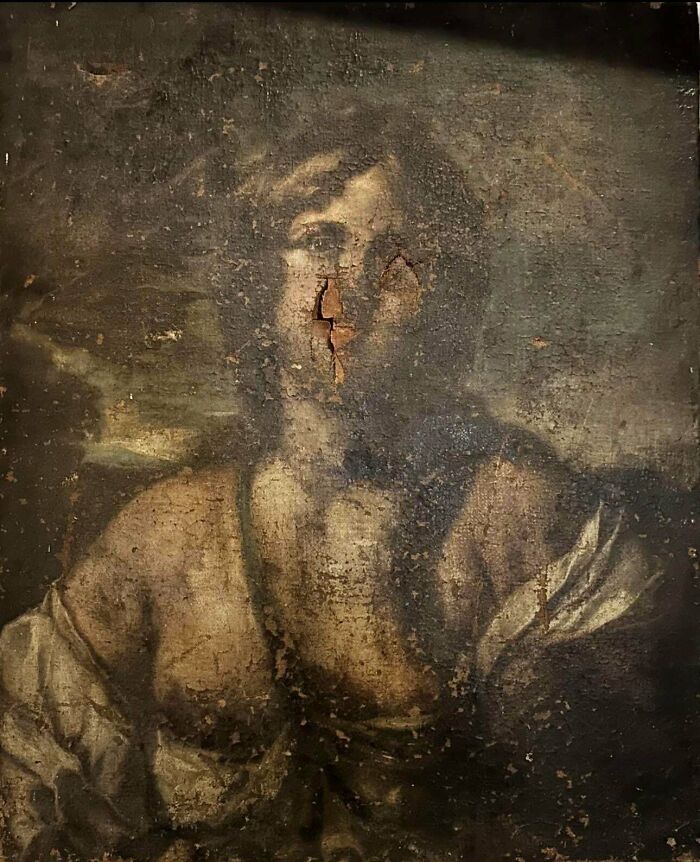 A damaged antique portrait painting of a person, showing remarkable artistic details beneath the peeling paint.