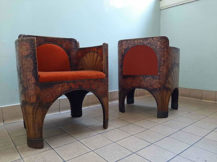 Two remarkable antique wooden chairs with ornate floral carvings and vibrant red upholstery, displaying craftsmanship.