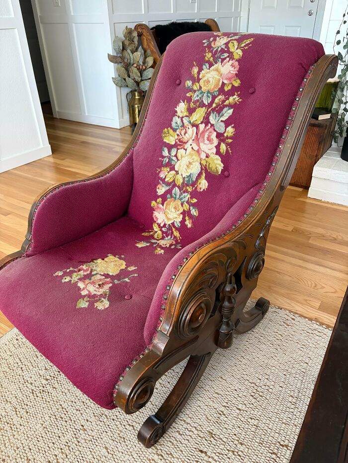 A remarkable antique rocking chair with ornate carved wood and deep red upholstery featuring an embroidered floral design.