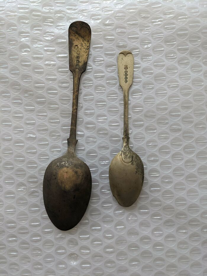 Two remarkable antique tarnished silver spoons of different sizes, showing wear and markings.