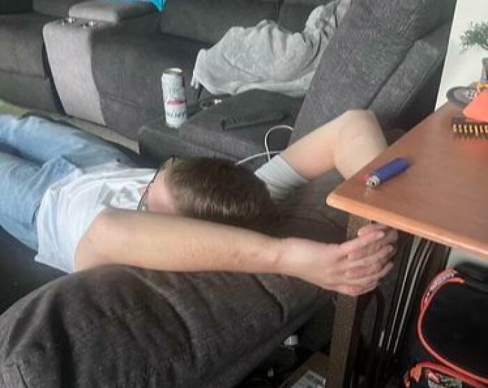 Person caught sleeping in hilarious ways, sprawled across a couch with arms stretched out in an unhinged posture.