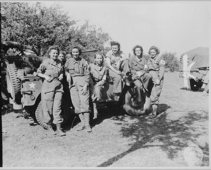 Seven women in uniform pose with a jeep, a fascinating image among these historical photos.