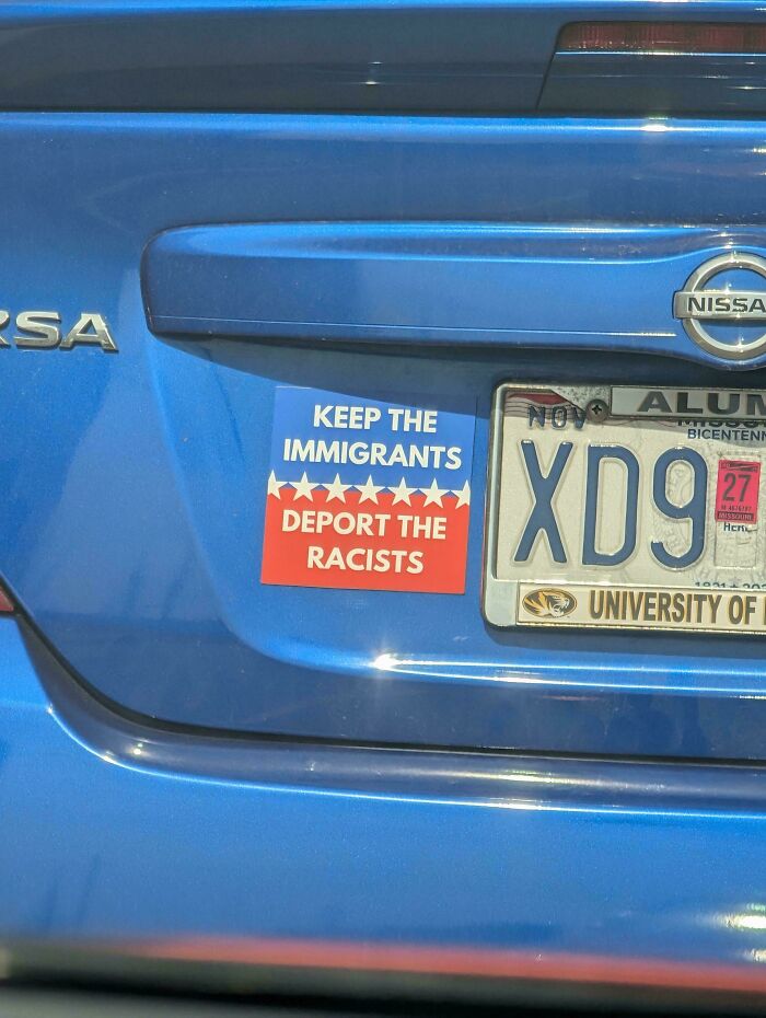Wild bumper sticker on a blue car saying "Keep the Immigrants, Deport the Racists."