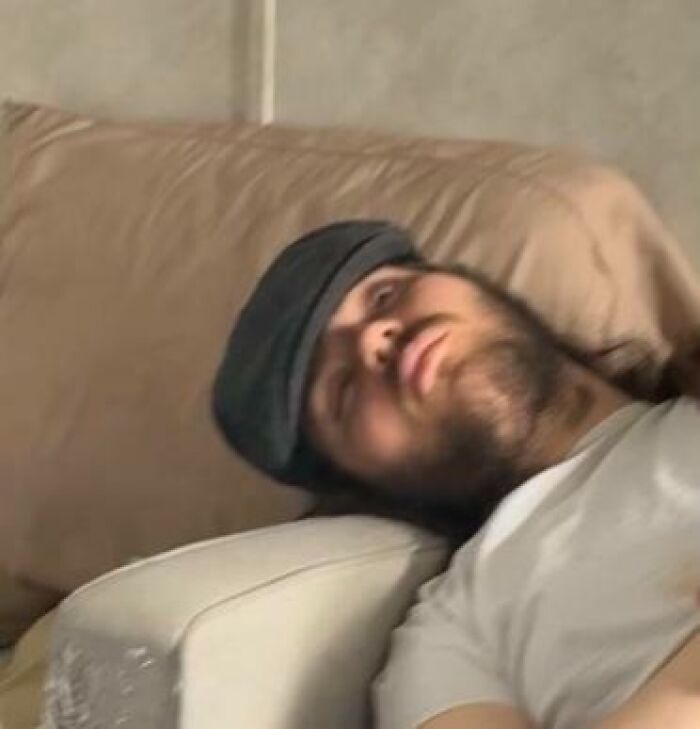 Man caught sleeping on couch with cap over eyes, showcasing one of the hilarious and unhinged ways people sleep.