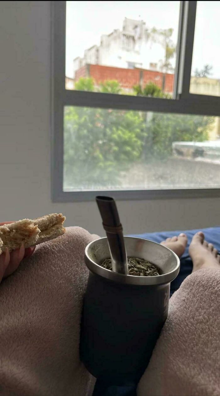Person holding sandwich with mate cup between legs appears like a confusing photo glitch in real life.