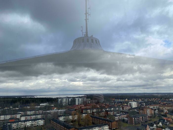 Reflection of a tower on window clouds create a misleading and confusing photo that looks like a glitch in real life.